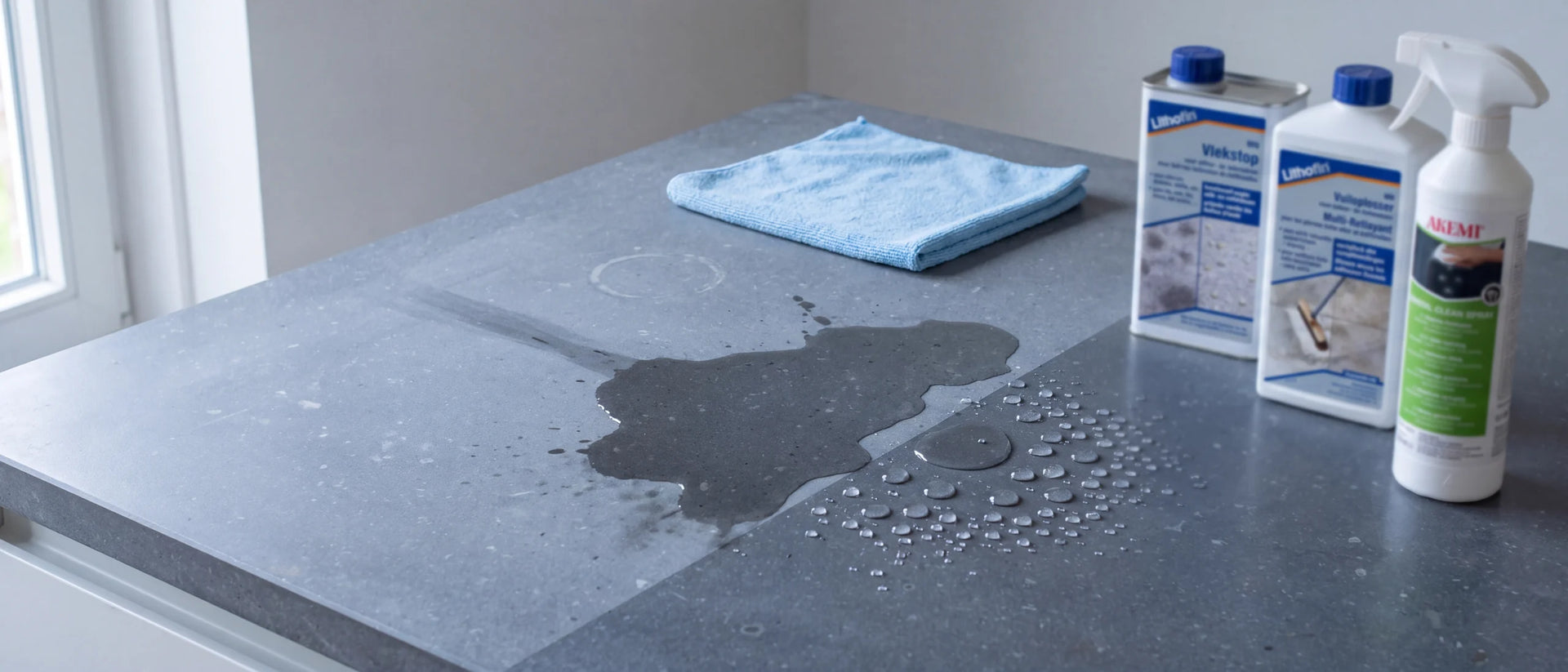 Aanrechtblad van Belgisch hardsteen: de linkerhelft is alleen schoongemaakt en dof, water trekt erin; de rechterhelft is gereinigd, beschermd en onderhouden en laat water parelen. Op het blad staan Lithofin MN Vlekstop, Lithofin MN Vuiloplosser en Akemi Crystal Clean spray.