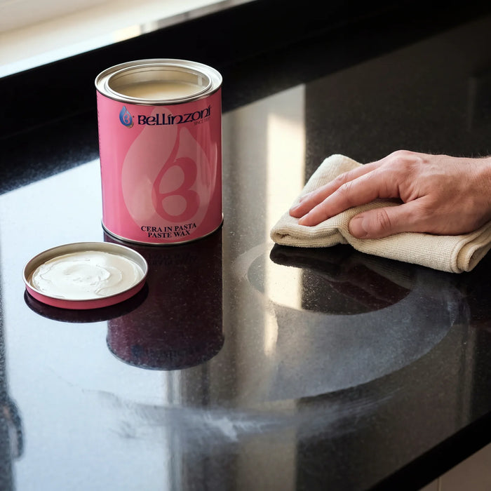 Zwart gepolijst graniet wordt opgewreven met een doek, naast een blik Bellinzoni paste wax